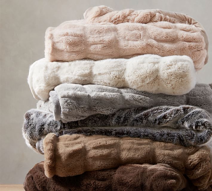 interior design trend-stack of comfy  plush throw blankets in different neutral colors. 