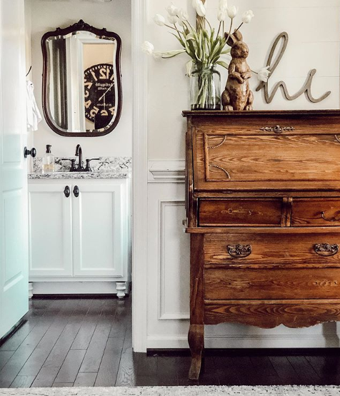 layering old and new interior design trend, antique desk, up to date bathroom with old mirror, granite vanity.