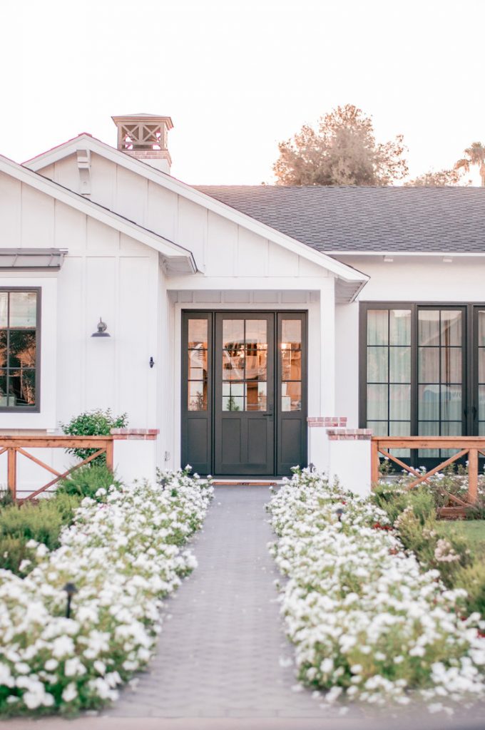 White house with gray door, and floral walkway, a simple and easy way to boost your curb appeal. 